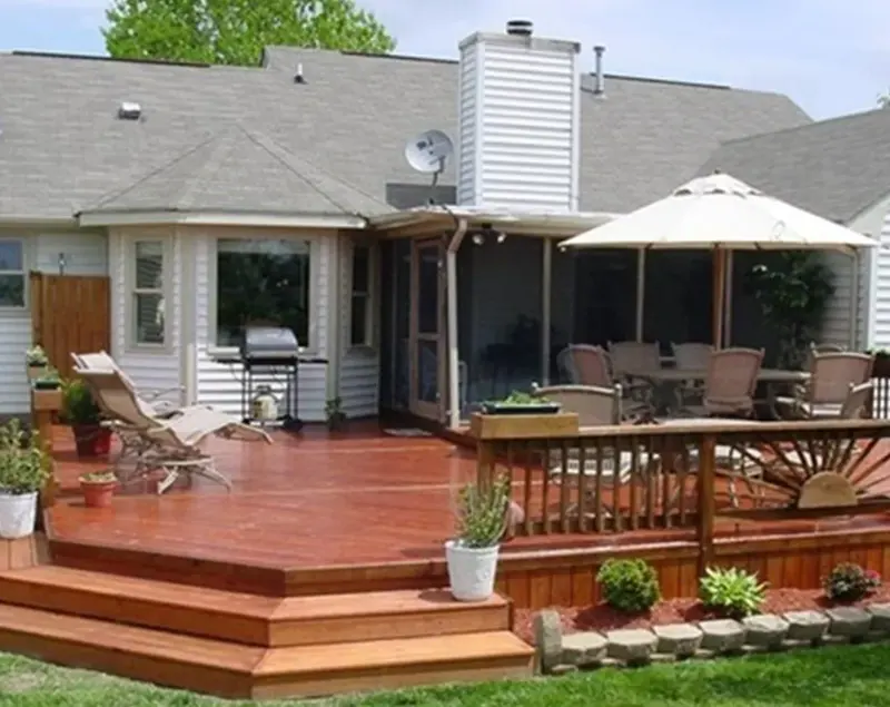 Tiered wood deck with built-in railing and planter beds behind a home